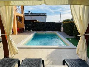 a swimming pool with two chairs and an umbrella at Boutique Apartment with Private Heated Pool in Novigrad Istria