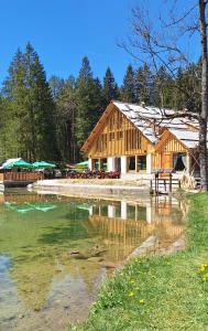a wooden building next to a body of water at Gostišče Jezersko in Zgornje Jezersko