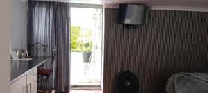 a kitchen with a room with a bed and a television on the wall at 16 on Point in Parow