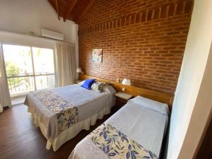 a bedroom with two beds and a brick wall at Costanera Mar Hotel & Suites in San Clemente del Tuyú +67 photos