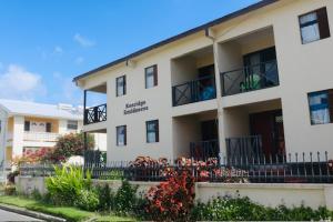 a white apartment building with a balcony and flowers at Kenridge Residences in Saint James