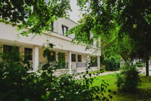 a white house with trees in front of it at Villa boZEN w Juracie in Jurata