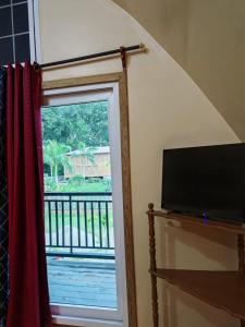 a window with a red curtain and a television at Cabaña Bungalow in Tela