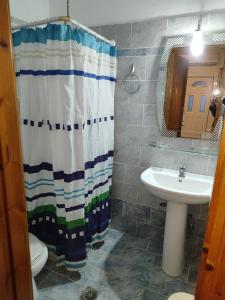 un bagno con tenda da doccia e lavandino di Basilis room a Loutsa