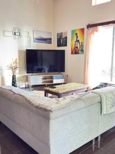 a living room with a couch and a flat screen tv at Villa Prisca in Sainte Marie