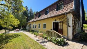 a yellow house with a table and chairs in front of it at Wienerwaldhof in Irenental