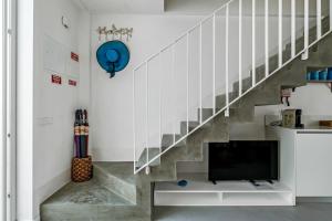 a living room with a staircase with a flat screen tv at The Blue House - Mediterranean Loft in Faro