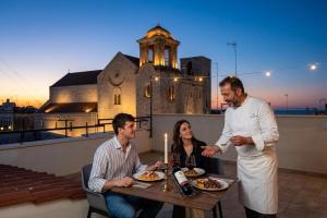 a man standing on a rooftop with two people eating food at Borgo Puglia in Bisceglie