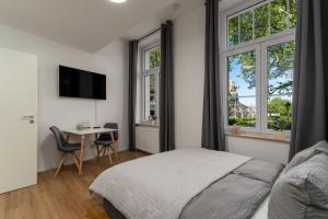 a bedroom with a bed and a desk and windows at Litzi's zentrales Apartment mit Parkplatz in Hockenheim