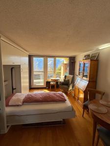 a bedroom with a bed and a desk and a chair at Blüemlisalp 712 Studio in Beatenberg +19 photos