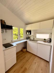 a kitchen with white cabinets and a wooden floor at Casetta a Lago in Onno +7 photos