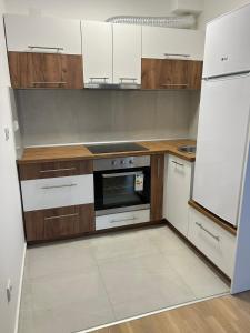 a kitchen with white appliances and wooden cabinets at Sabac City Apartman Centar S2 in Šabac