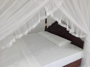 Cama en habitación con cortinas blancas en Mirissa Cocoon, en Mirissa