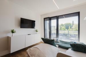 a white living room with a tv and a couch at Premium Studio mit Balkon - Pfarrkirchen in Pfarrkirchen