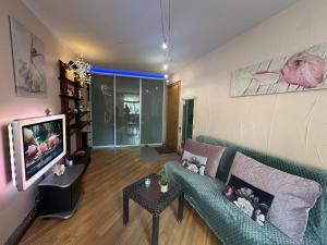 a living room with a couch and a tv at Andrea Apartamenti in Jūrmala