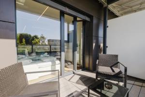 a balcony with glass doors and two chairs and a tub at Premium Studio mit Balkon - Pfarrkirchen in Pfarrkirchen