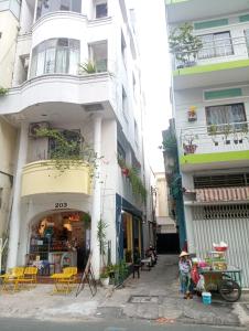 a tall white building with a store on a street at CAMP Dakao a curated accomodation in Ho Chi Minh City