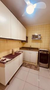 a kitchen with white cabinets and a microwave at Espaço tranquilo e de lazer em Guarujá in Guarujá