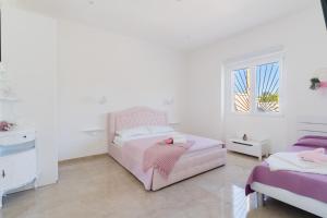 a white bedroom with two beds and a window at Domus Afrodite - Torre Squillace in Torre Squillace