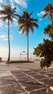 two palm trees on a beach with the ocean at Espaço tranquilo e de lazer em Guarujá in Guarujá