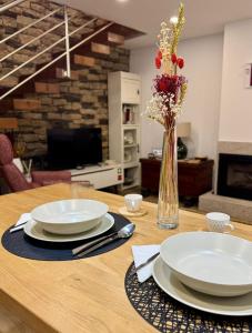 a wooden table with two plates and a vase with flowers at Casas do Abô Fredo in Sendim