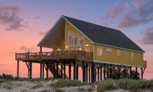 a yellow house on a pier on the beach at DayDreamer Beachfront w 7 Bedrooms in Gilchrist