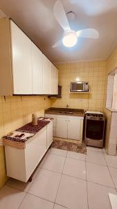 a kitchen with white cabinets and a ceiling fan at Espaço tranquilo e de lazer em Guarujá in Guarujá +10 photos