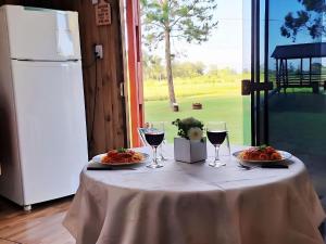 a table with two plates of food and glasses of wine at Cabana com Estacionamento ll Internet l Nomade Digital ll Táxi Fácil II Fogão Peq ll Quiosque Churrasqueira ll 5km da ERS-030 Km 88 ll 7Km da Prefeitura l Câmara Mun I IFRGS II 7,2Km UFRGS Litoral II l 12km-Praias in Osório