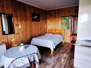 two beds in a room with wooden walls at Cabana com Estacionamento ll Internet l Nomade Digital ll Táxi Fácil II Fogão Peq ll Quiosque Churrasqueira ll 5km da ERS-030 Km 88 ll 7Km da Prefeitura l Câmara Mun I IFRGS II 7,2Km UFRGS Litoral II l 12km-Praias in Osório
