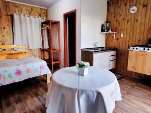 a bedroom with a bed and a table with flowers on it at Cabana com Estacionamento ll Internet l Nomade Digital ll Táxi Fácil II Fogão Peq ll Quiosque Churrasqueira ll 5km da ERS-030 Km 88 ll 7Km da Prefeitura l Câmara Mun I IFRGS II 7,2Km UFRGS Litoral II l 12km-Praias in Osório