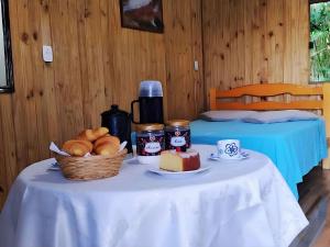 a table with a basket of bread and coffee on it at Cabana com Estacionamento ll Internet l Nomade Digital ll Táxi Fácil II Fogão Peq ll Quiosque Churrasqueira ll 5km da ERS-030 Km 88 ll 7Km da Prefeitura l Câmara Mun I IFRGS II 7,2Km UFRGS Litoral II l 12km-Praias in Osório