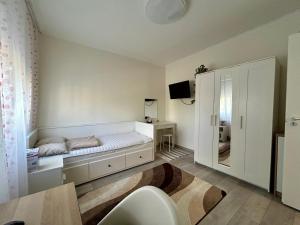 a white bedroom with a bed and a tv at Tulipán Apartman Csongrád in Csongrád