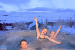 três crianças estão a nadar numa banheira de hidromassagem em Torsetlia Cottages and Apartments em Uvdal