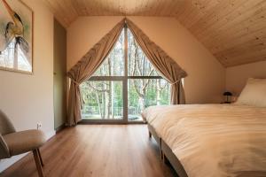 a bedroom with a bed and a large window at Domki Poleskie Stodoły in Stare Załucze