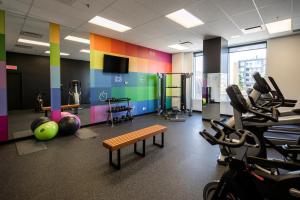 ein Fitnessstudio mit Trainingsgeräten und einer Bank in einem Raum in der Unterkunft Hôtel Alt Quartier DIX30 in Brossard