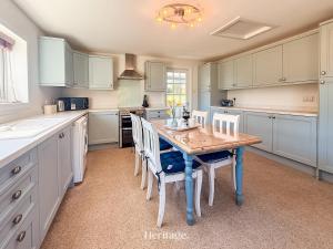 a kitchen with a wooden table and white cabinets at Nether Clashnoir, Glenlivet in Knockandhu