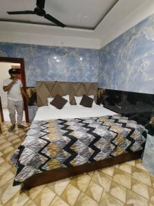 a man is standing in a bedroom with a bed at Tulsi Dham in Vrindāvan +2 photos