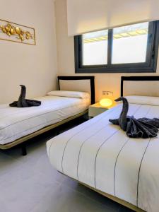 two beds in a room with two swans on them at Skyline Infinity Apartment Eagle Tower Benidorm in Benidorm +46 photos