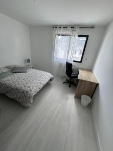 a bedroom with a bed and a desk and a chair at Maison proximité de la plage in Plouzané