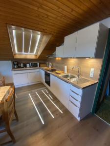 a kitchen with white cabinets and a wooden ceiling at Gästehaus Grieser in Hopferau