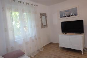 a living room with a flat screen tv and a window at Apartman Perina in Trogir