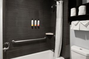 a bathroom with a shower with two bottles on the wall at Pacific Inn Monterey in Monterey +26 photos