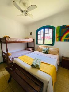 a bedroom with two beds and a ceiling fan at Hostel dos Gring0s in Maricá