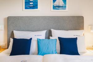 a bed with blue and white pillows on it at Am Horizont 3 modern und stilvoll Garten Strandkorb Nähe Strand und Hafen WLAN und Parkplatz inklusiv in Zingst