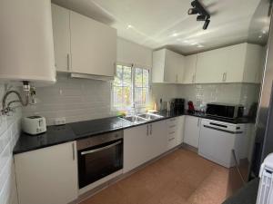 a kitchen with white cabinets and black counter tops at Rdj B in Porto Moniz