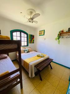 a bedroom with two beds and a ceiling fan at Hostel dos Gring0s in Maricá