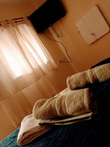 a pile of towels sitting on a bed next to a lamp at Misky Sonqo in Tilcara
