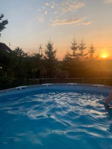 a large swimming pool with a sunset in the background at Spokojna Dolina in Brejdyny