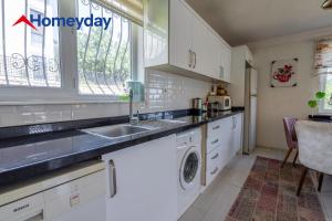 a kitchen with white cabinets and a sink and a window at Villa Mountain with Pool in Gedeller