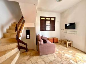 a living room with a couch and a tv and stairs at Triplex em Maracajaú a beira-mar in Maxaranguape